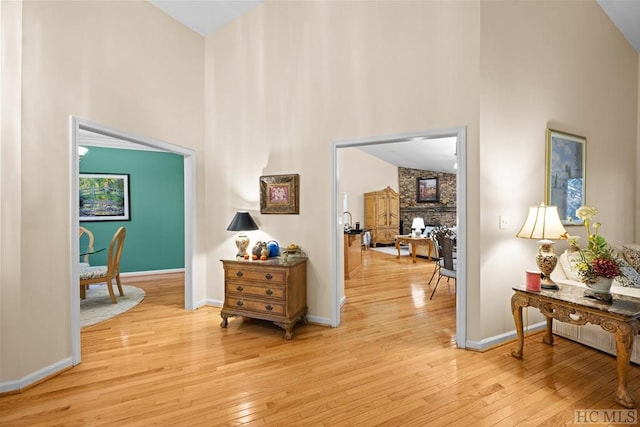 hall featuring light hardwood / wood-style flooring and high vaulted ceiling