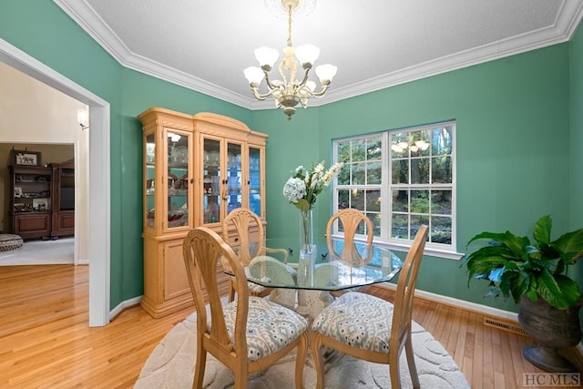 dining room with an inviting chandelier, light hardwood / wood-style flooring, and ornamental molding