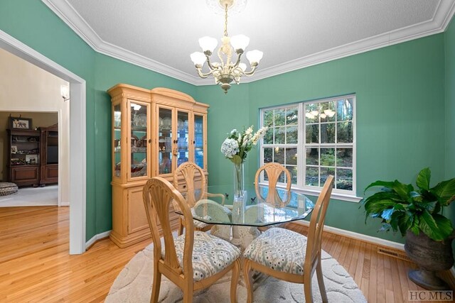 dining area featuring a chandelier, crown molding, and light hardwood / wood-style flooring