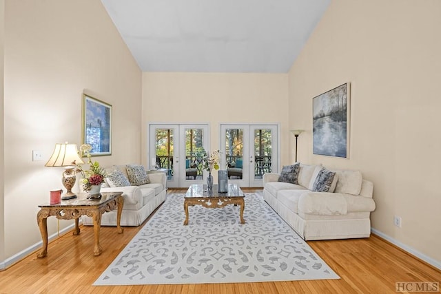 living room with french doors, high vaulted ceiling, and light hardwood / wood-style floors