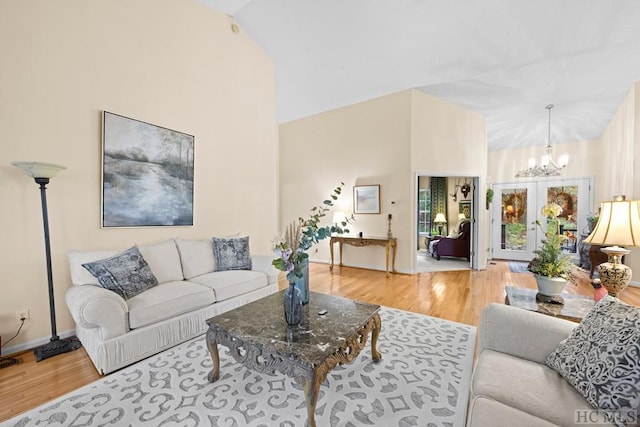 living room with a notable chandelier, hardwood / wood-style flooring, and vaulted ceiling