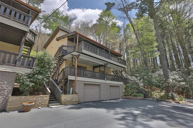 125 Hawks Nest Ln Unit 1, Highlands, NC 28741 - view of front facade with a balcony, an attached garage, stairs, stone siding, and aphalt driveway