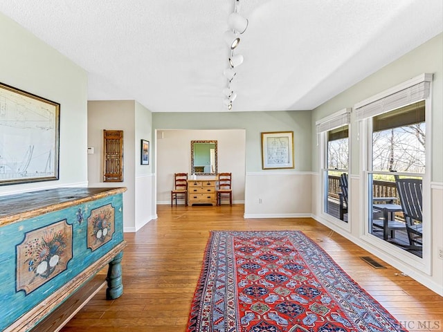 interior space featuring hardwood / wood-style floors, rail lighting, and a textured ceiling