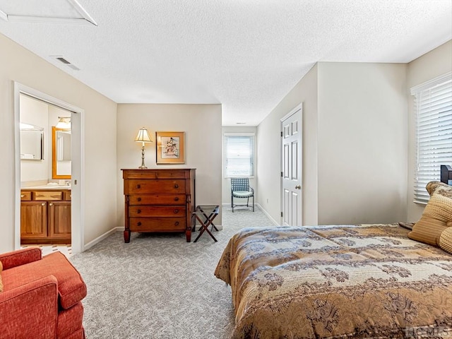 carpeted bedroom featuring a textured ceiling and ensuite bathroom