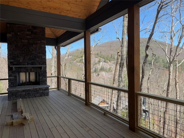 wooden deck with a mountain view and an outdoor stone fireplace
