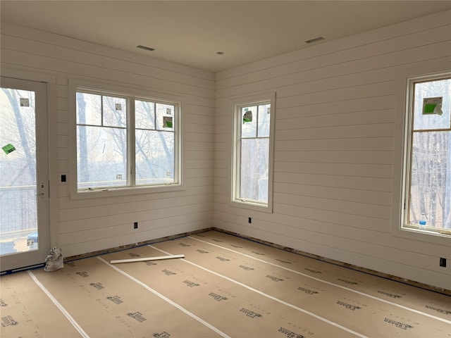 unfurnished room with visible vents and wooden walls