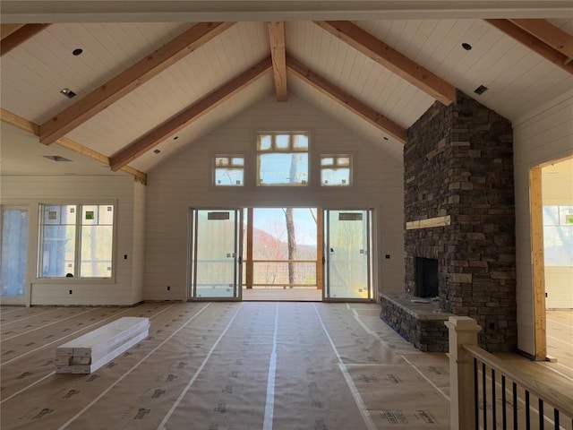 unfurnished living room featuring a fireplace, beam ceiling, and high vaulted ceiling