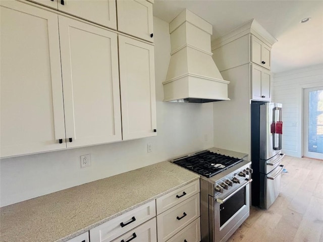 99 Sori Ln, Sapphire, NC 28774 - kitchen featuring appliances with stainless steel finishes, custom exhaust hood, light wood-type flooring, light stone counters, and white cabinets