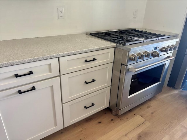 99 Sori Ln, Sapphire, NC 28774 - kitchen with high end stainless steel range oven, light wood-type flooring, white cabinetry, and light stone countertops
