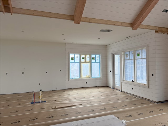 empty room with light wood-style floors and beam ceiling