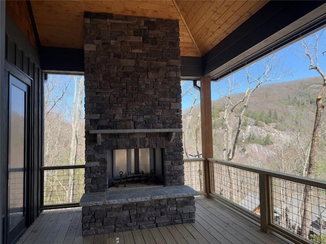 wooden terrace featuring an outdoor stone fireplace and a mountain view