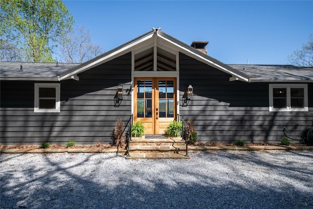 entrance to property featuring french doors and a shingled roof