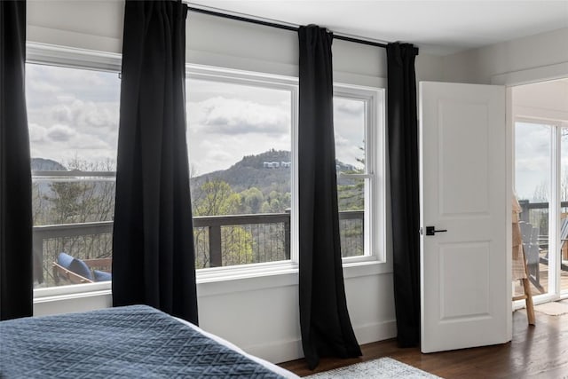 bedroom with multiple windows, a mountain view, and dark wood-style flooring