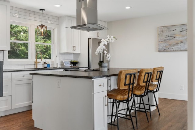 kitchen featuring a kitchen breakfast bar, a kitchen island, island range hood, dark countertops, and dark wood-style floors
