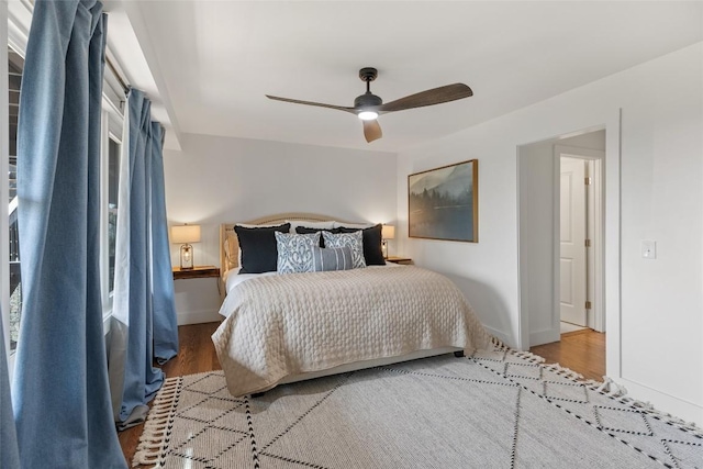 bedroom with baseboards, ceiling fan, and wood finished floors
