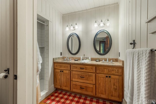 bathroom featuring vanity, a shower, and wood walls