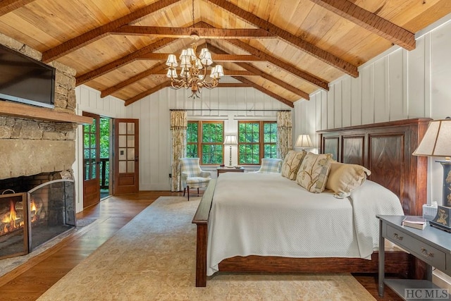 bedroom with lofted ceiling with beams, a stone fireplace, hardwood / wood-style floors, and multiple windows