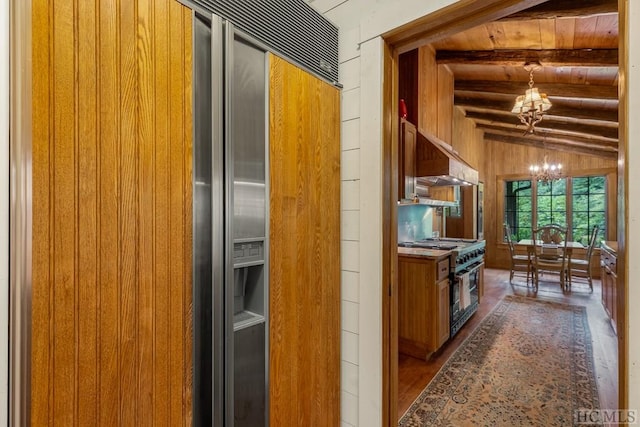 kitchen with wood ceiling, vaulted ceiling with beams, wooden walls, high end appliances, and a chandelier