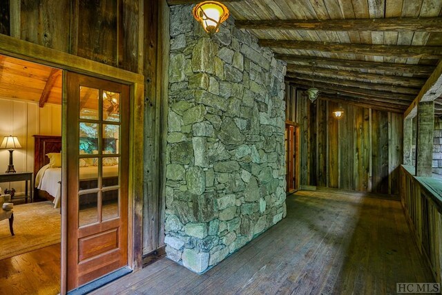 interior space with lofted ceiling with beams, hardwood / wood-style flooring, wood ceiling, and wood walls