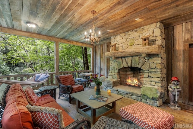 sunroom with a stone fireplace, a healthy amount of sunlight, an inviting chandelier, and wood ceiling