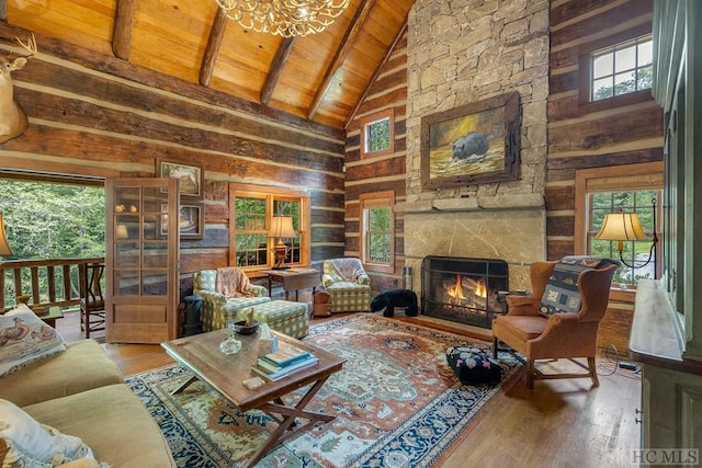 living room featuring beam ceiling, wooden walls, high vaulted ceiling, a stone fireplace, and wooden ceiling