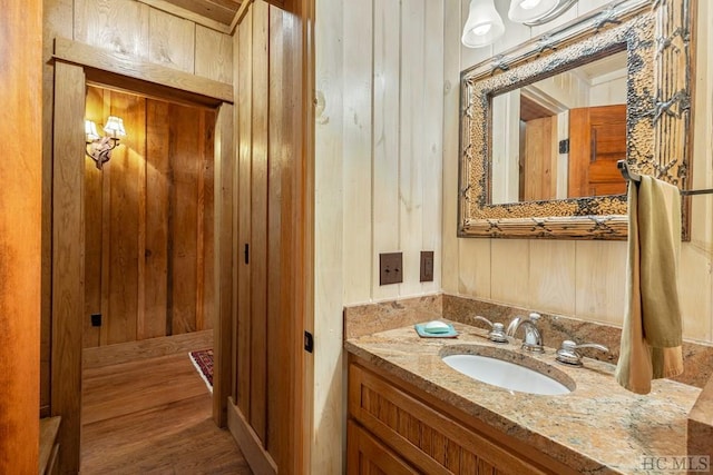 bathroom featuring vanity, wood-type flooring, and wooden walls