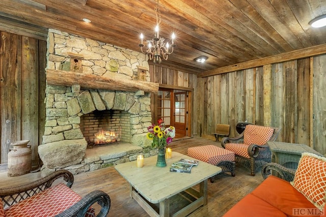 sitting room featuring a stone fireplace, wood ceiling, a chandelier, wooden walls, and hardwood / wood-style floors