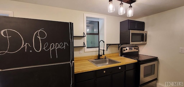 kitchen with appliances with stainless steel finishes, sink, and hanging light fixtures