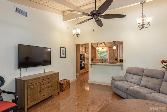 living room featuring ceiling fan with notable chandelier, beamed ceiling, sink, wood ceiling, and light wood-type flooring