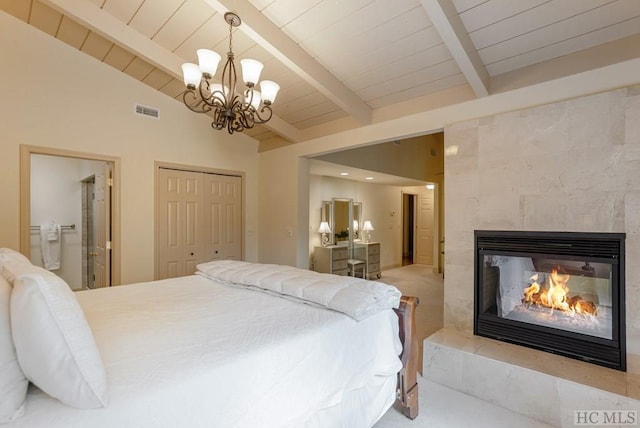 bedroom featuring vaulted ceiling with beams, connected bathroom, a fireplace, a closet, and a chandelier