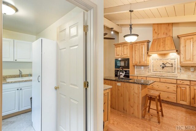 kitchen with a kitchen island, beamed ceiling, tasteful backsplash, sink, and black appliances