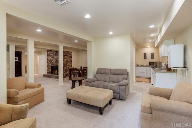 living room featuring light colored carpet, a fireplace, and sink