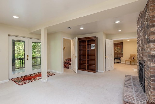 interior space with a brick fireplace, light colored carpet, and french doors