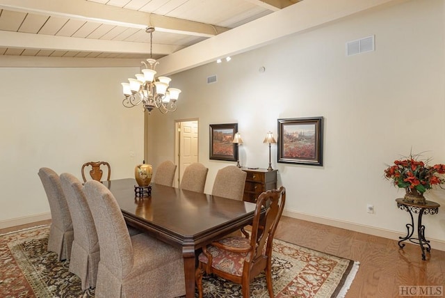 dining area featuring hardwood / wood-style floors, vaulted ceiling with beams, an inviting chandelier, and wood ceiling