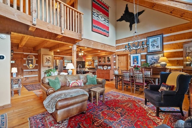 living room featuring wood walls, a wood stove, beamed ceiling, a towering ceiling, and hardwood / wood-style floors