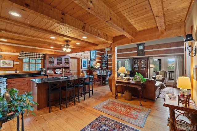 living room with wooden walls, sink, beam ceiling, and wooden ceiling