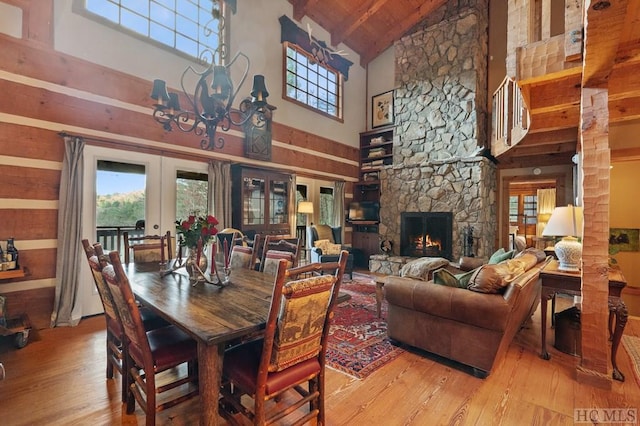 dining area featuring a stone fireplace, high vaulted ceiling, and french doors