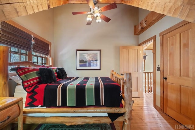 bedroom with ceiling fan, high vaulted ceiling, and light hardwood / wood-style flooring