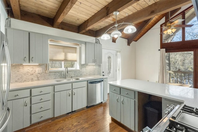 kitchen featuring sink, vaulted ceiling with beams, hanging light fixtures, appliances with stainless steel finishes, and decorative backsplash