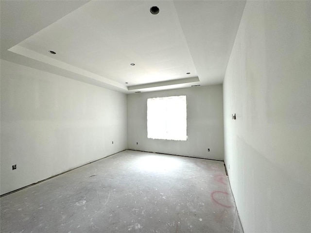 spare room with a tray ceiling and concrete floors