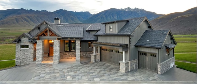 view of front facade featuring stone siding, a chimney, decorative driveway, and a mountain view