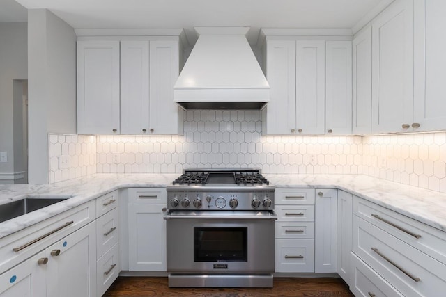 kitchen featuring high end stainless steel range oven, premium range hood, white cabinetry, decorative backsplash, and light stone counters