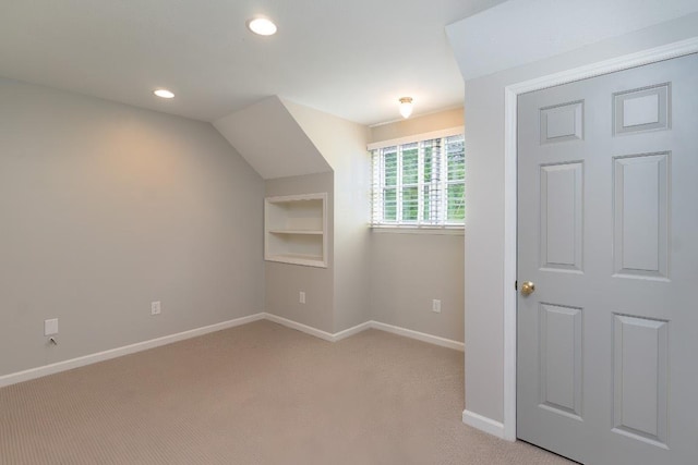 additional living space featuring baseboards, built in shelves, light colored carpet, and recessed lighting