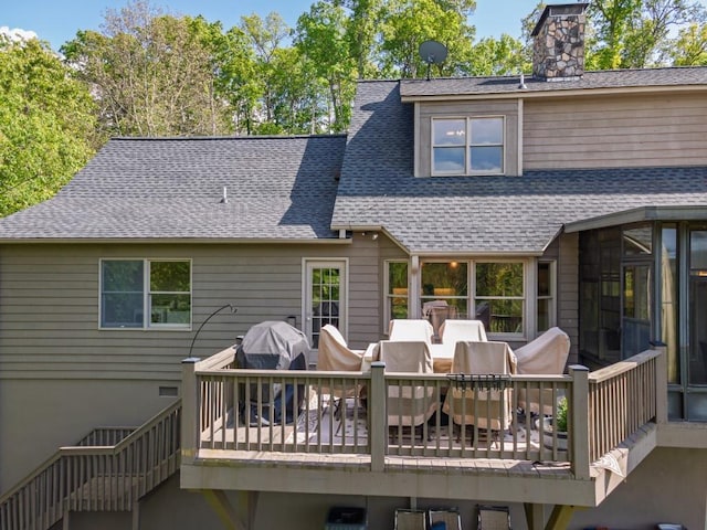 back of property featuring roof with shingles, outdoor dining area, a chimney, and a deck