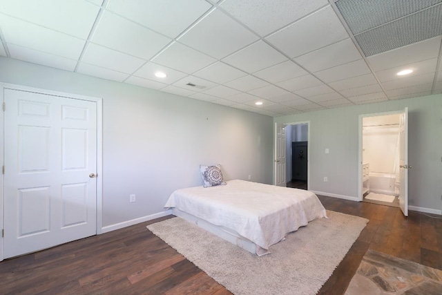 bedroom featuring baseboards, dark wood-style flooring, recessed lighting, connected bathroom, and a drop ceiling
