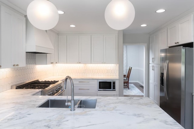 kitchen featuring stainless steel appliances, a sink, white cabinets, light stone countertops, and recessed lighting