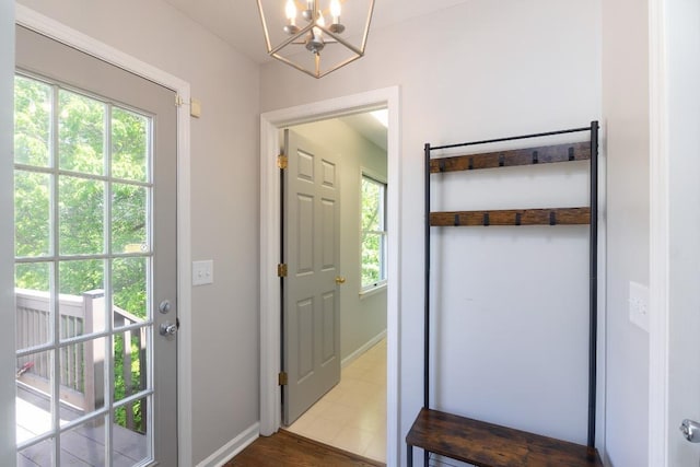 entryway featuring a chandelier, plenty of natural light, dark wood-style flooring, and baseboards