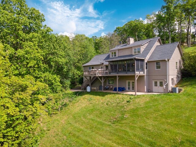 back of house featuring french doors, a sunroom, a patio area, a lawn, and a chimney