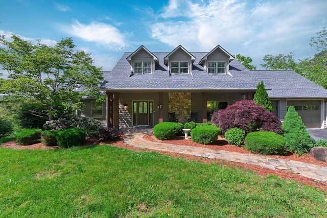 view of front of home with a front yard, an attached garage, a porch, stone siding, and a shingled roof
