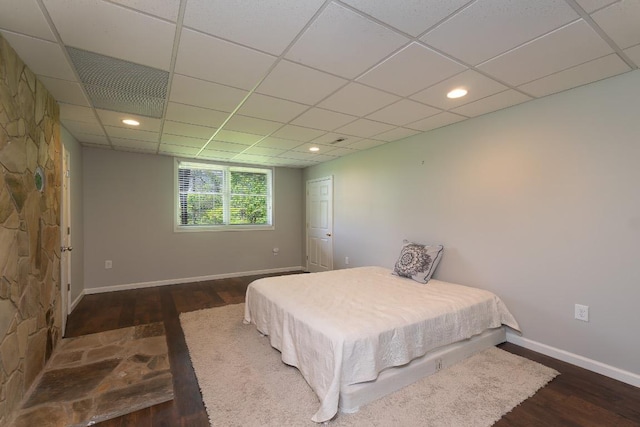 bedroom with wood finished floors, baseboards, and a drop ceiling